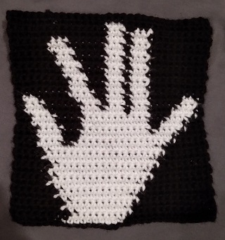 crocheted white hand on black background